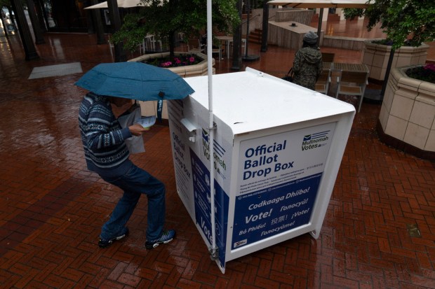 FILE – A person drops off their vote-by-mail ballot at...