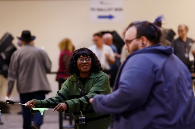 Poll worker Susan Henry directs voters to check in for...