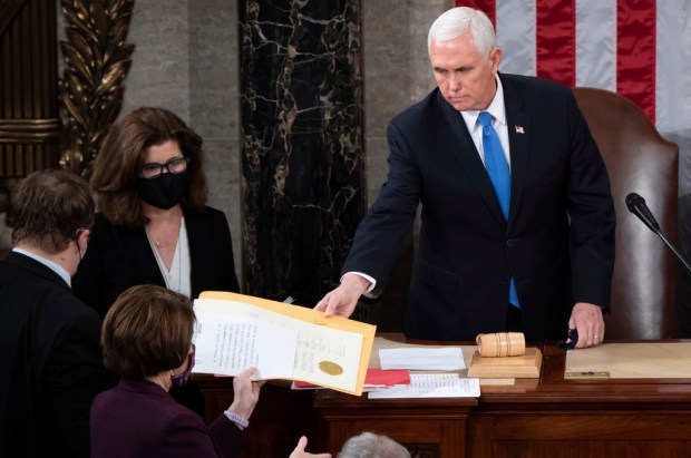 FILE – Vice President Mike Pence hands the electoral certificate...