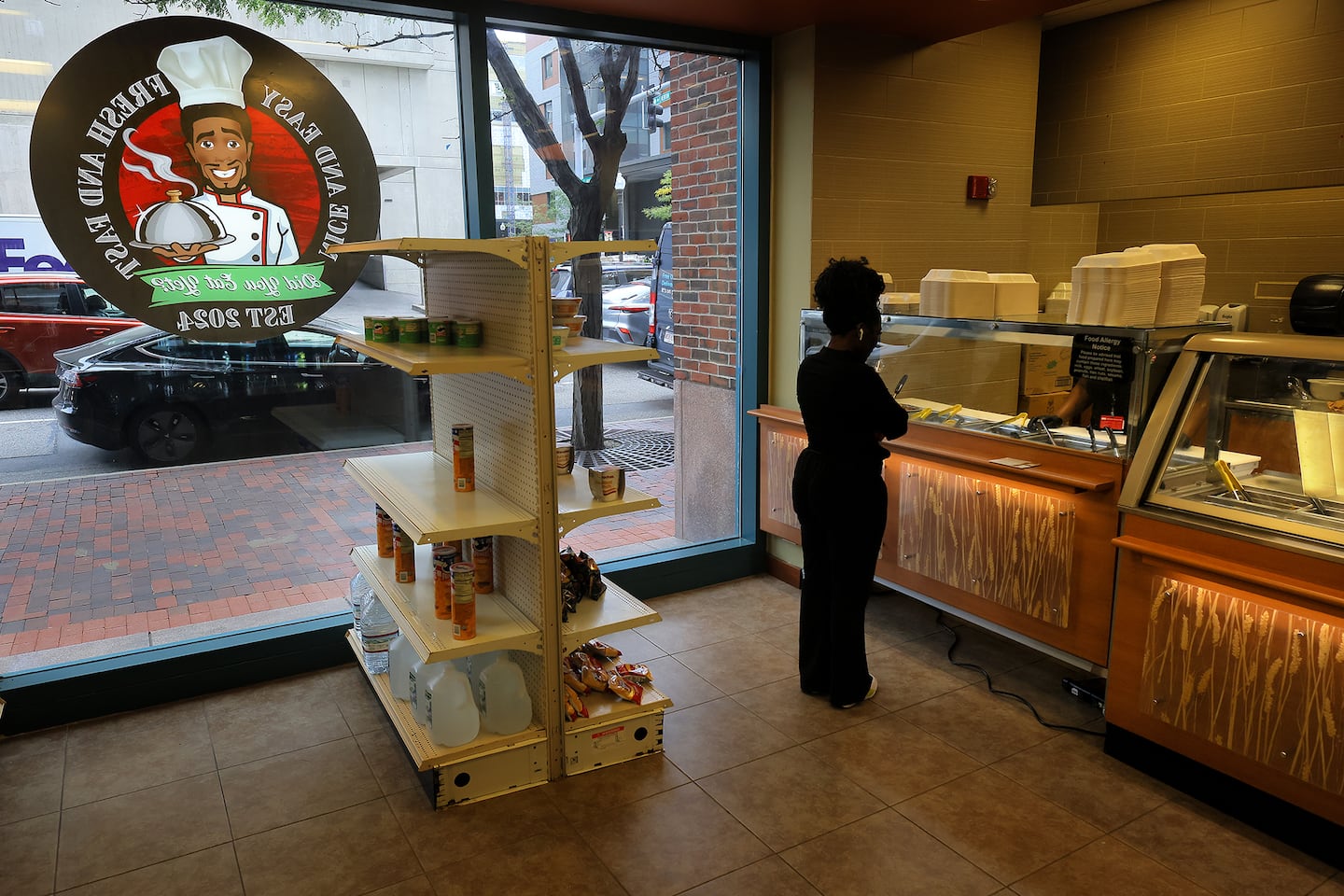 As a caricature of chef-owner Mirbentz Jean Francois looks down from the window, a customer waits for lunch to be served at Did You Eat Yet? in the South End.