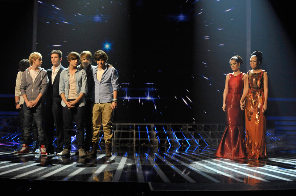 One Direction with Simon Cowell and Cheryl with Rebecca Ferguson in the final of The X Factor 2010. (Ken McKay/Talkback Thames/Shutterstock)