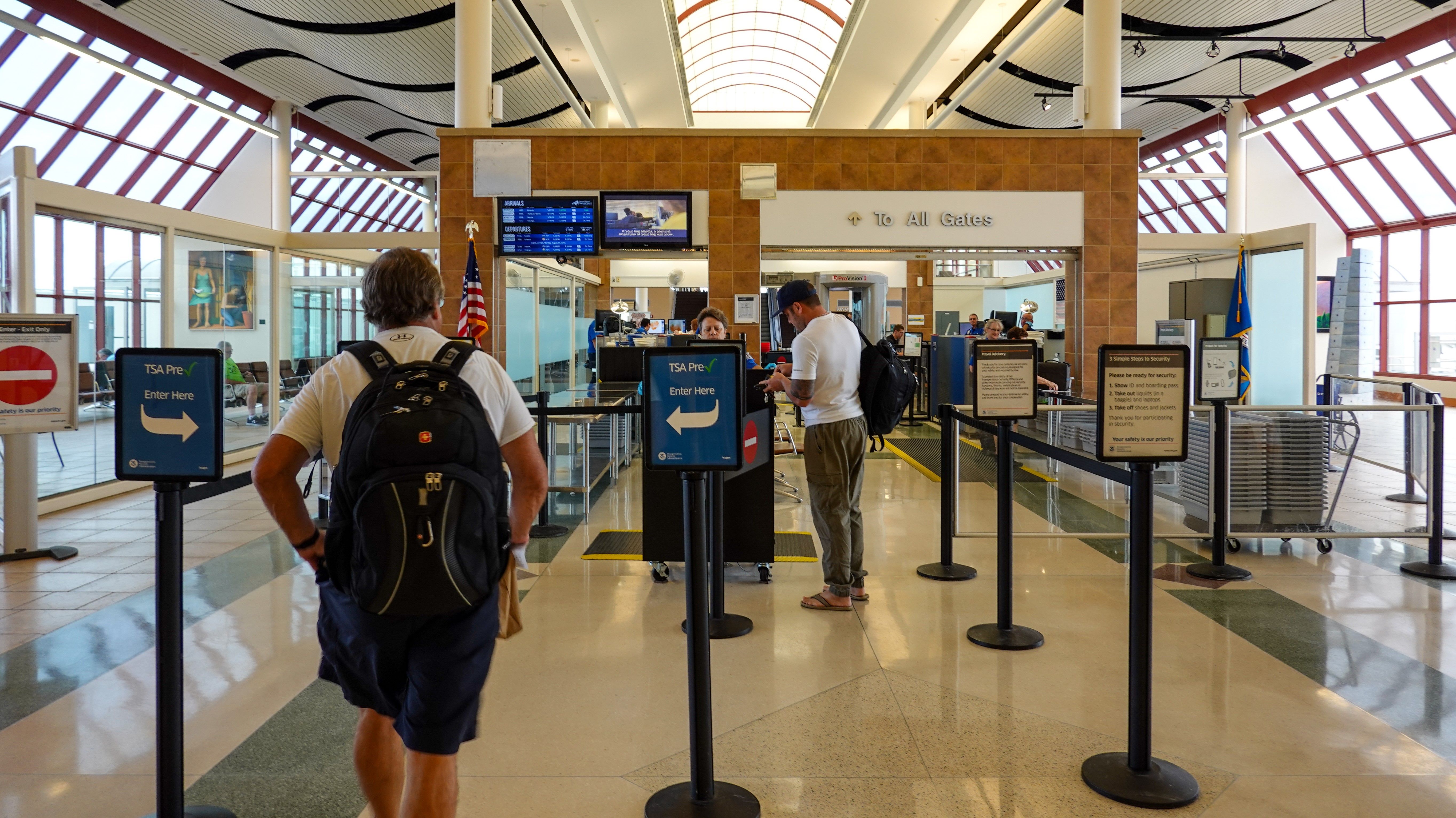 Person going through TSA Precheck line and regular line through airport security.