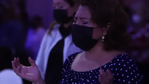 Woman with eyes closed and hands raised in a church