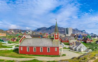 A red church in front of colorful buildings in Nuuk, Greenland