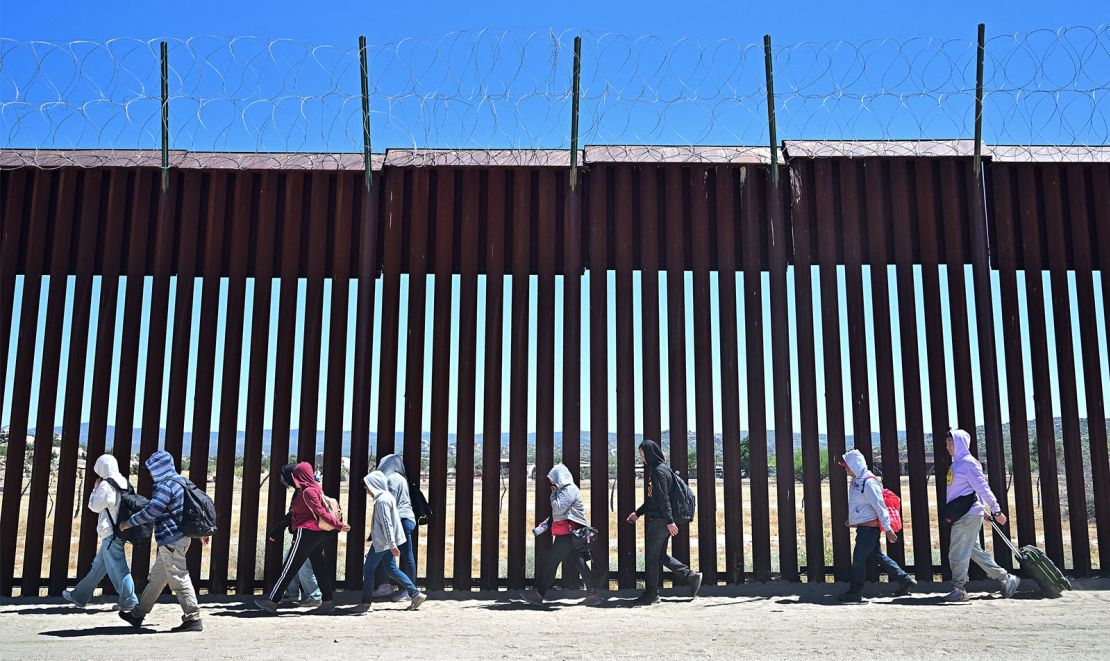 Migrants walk on the US side of the border wall in Jacumba Hot Springs, California, on June 5, after crossing from Mexico. 