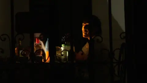 Person sits at a table in the dark, with drinks