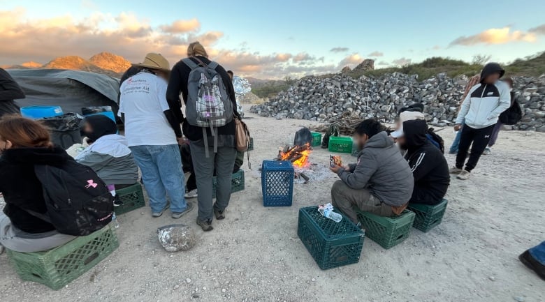 A group of people around a small fire in the desert