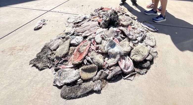 People stand outside in a courtyard, beside a pile of shoes.