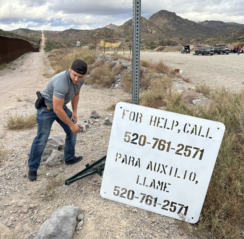 A man works to erect a sign offering a helpline in the Arizona desert