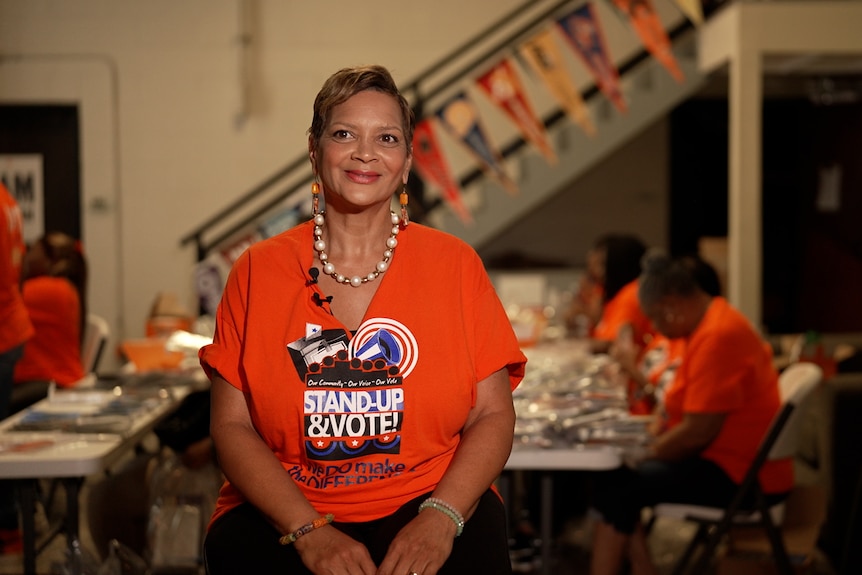 A woman smiles in an orange Georgia Stand UP campaign t-shirt