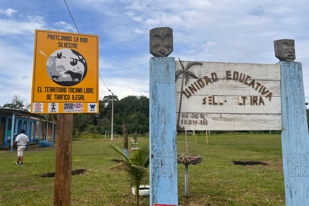 The entrance sign at Bella Altura, a Tacana town in the Bolivian Amazon rainforest. The sign on the left says: