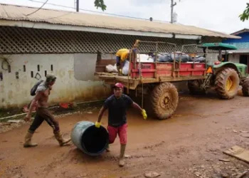 AFP Garbagemen pick up trash in Port Kaituma, Guyana, on September 21, 2022, in front of a garbage truck on a road.