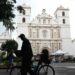 A man walks by on his bicycle in front of the San Miguel Arcangel Cathedral in the historic center of Tegucigalpa.