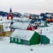 BBC A town in typical Greenland style is pictured - brightly-painted wooden walls and triangular roofs covered in snow are the main features of these sparsely dotted homes