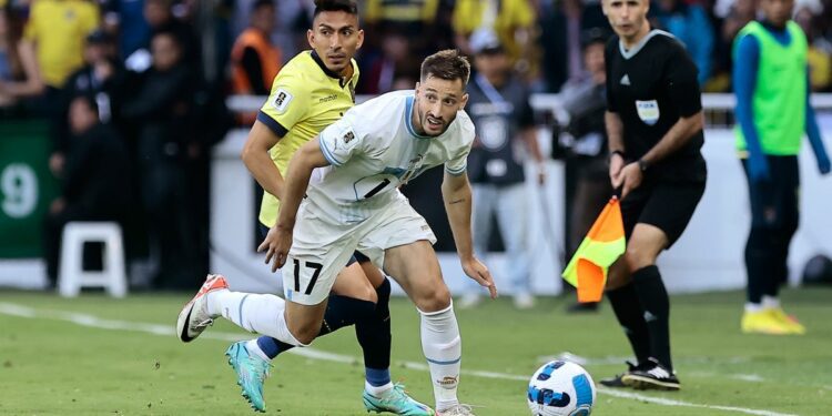 Matias Viña (R), in white kit, takes control of the ball with Rodrigo Paz Delgado, in yellow and black, not far behind, during Uruguay vs Ecuador.