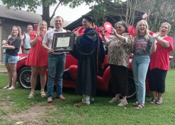 Tyler Huggins, center left, accepts his diploma from Kerry Melton of the College of Engineering while his wife, Anna, to his right, celebrates with other family members in Bono on June 26.