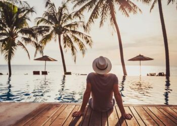 tourist in luxury beach hotel near luxurious swimming pool at sunset, tropical exotic holidays vacation, tourism and travel