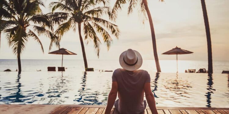 tourist in luxury beach hotel near luxurious swimming pool at sunset, tropical exotic holidays vacation, tourism and travel