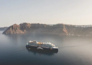 Celebrity Cruises ship anchored in calm waters near the cliffs of Santorini, Greece.