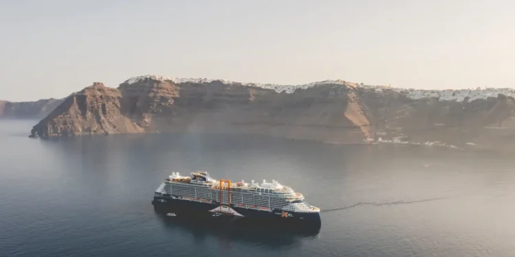 Celebrity Cruises ship anchored in calm waters near the cliffs of Santorini, Greece.