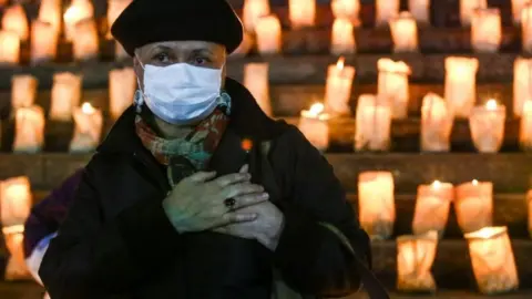 Reuters A woman clutches her heart at a candlelit memorial in Brazil