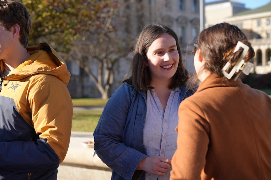 A woman in a blue jacket shakes hands with another woman 