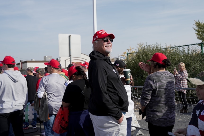 A man in a red cap stands in a crowd