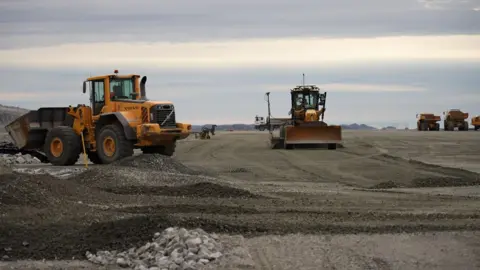 Trucks and diggers on Nuuk Airport's runway.