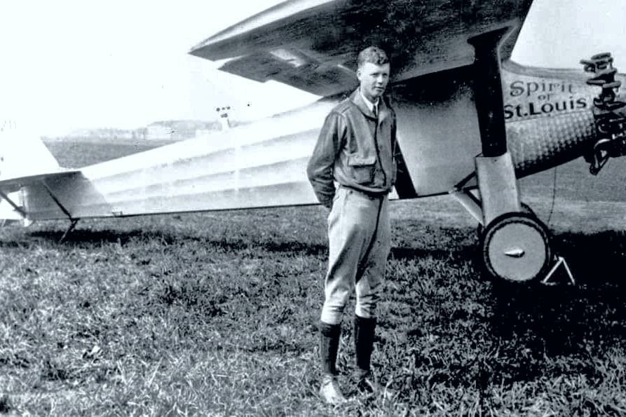 Charled Lindbergh standing in front of the Spirit of St Louis aircraft.