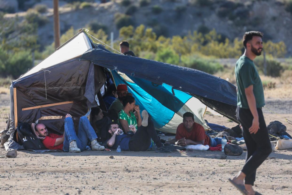 Migrants and asylum seekers gather in a makeshift camp after crossing the border.