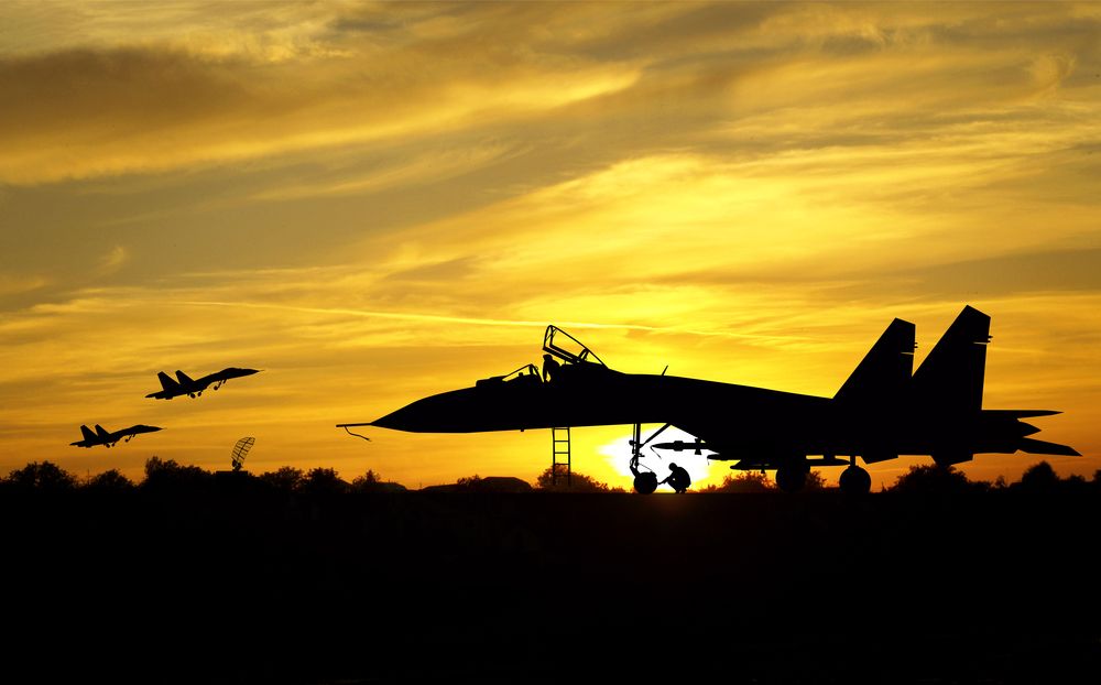 Several Fighter jets taking off against a sunset.