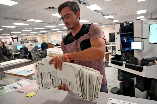 An elections official sorts counted mail-in ballots on the first day of tabulation