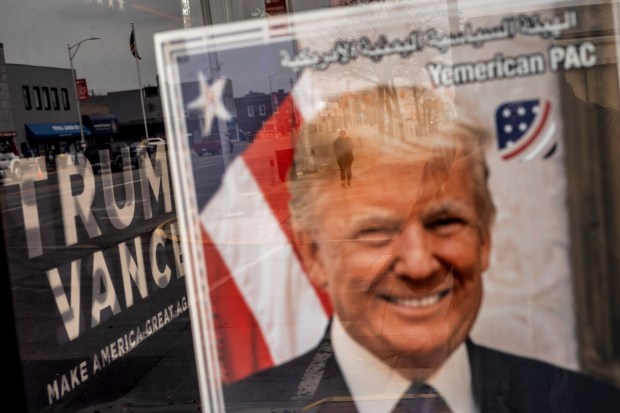 An image of Republican presidential nominee former President Donald Trump hangs in the window of a campaign office as a pedestrian passes by