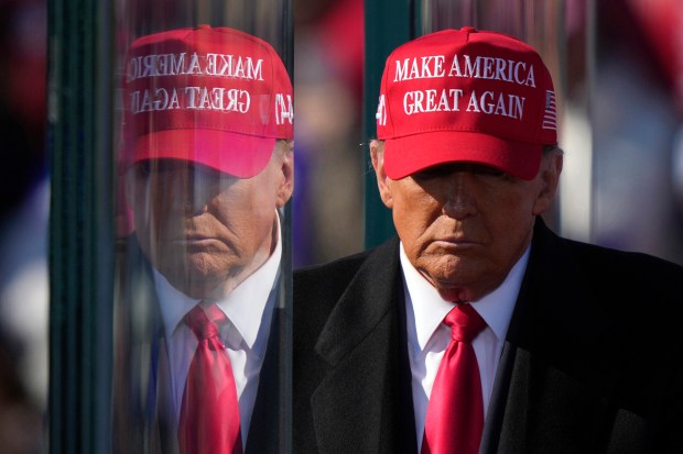 Republican presidential nominee former President Donald Trump is reflected in the bullet proof glass as he finishes speaking at a campaign rally