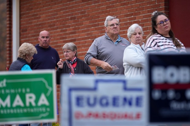 Voters stand in line while waiting for a polling place...