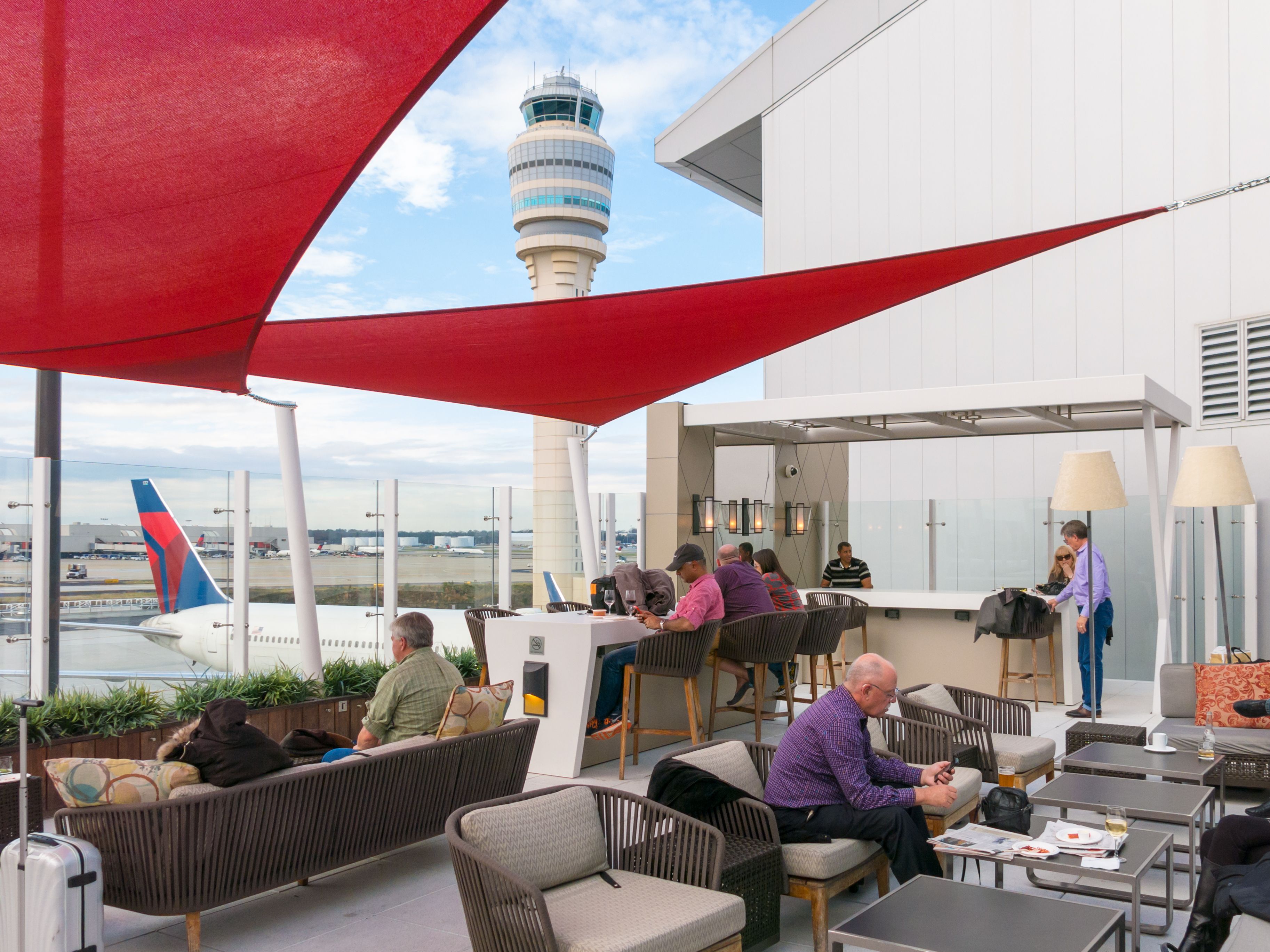 Passengers enjoying food and apron views at the Delta Sky Club lounge at Hartsfield Jackson Atlanta International Airport.