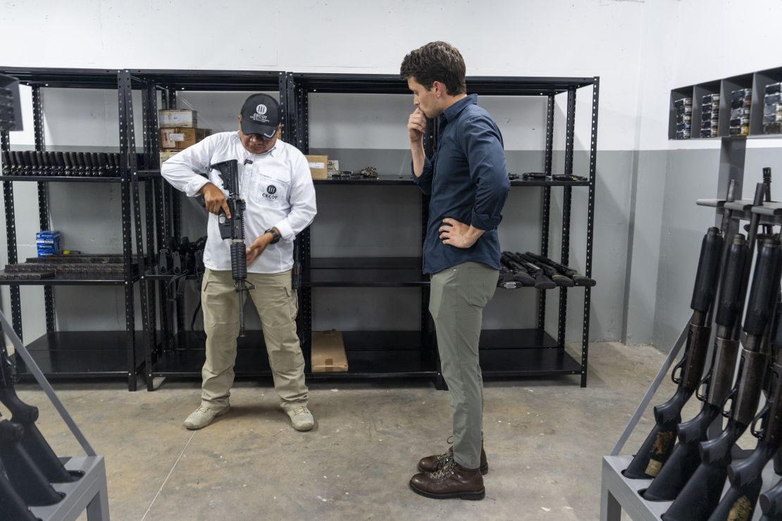 Prison director Belarmino García, seen here in the armory with CNN's David Culver, right, says the harsh restrictions of Cecot are both justified and necessary.