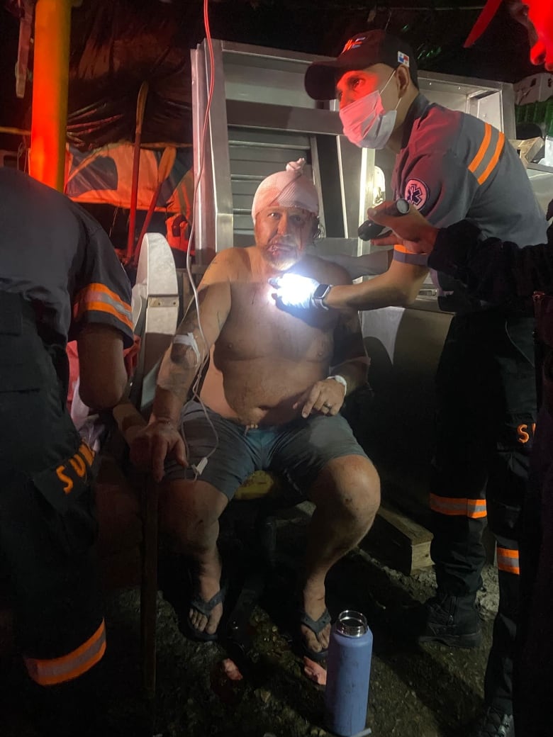 Man sits bleeding with paramedics in ambulance. 