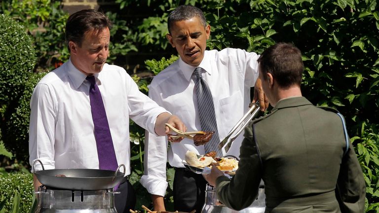 Britain's Prime Minister David Cameron (L) and U.S. President Barack Obama serve food to a guest at a barbecue in the garden of 10 Downing Street, in central London May 25, 2011. U.S. President Barack Obama and British Prime Minister David Cameron on Wednesday will stress a united effort to pressure Libyan leader Muammar Gaddafi to step down, while glossing over differences between their two governments. REUTERS/Matt Dunham/Pool (BRITAIN - Tags: POLITICS IMAGES OF THE DAY)
