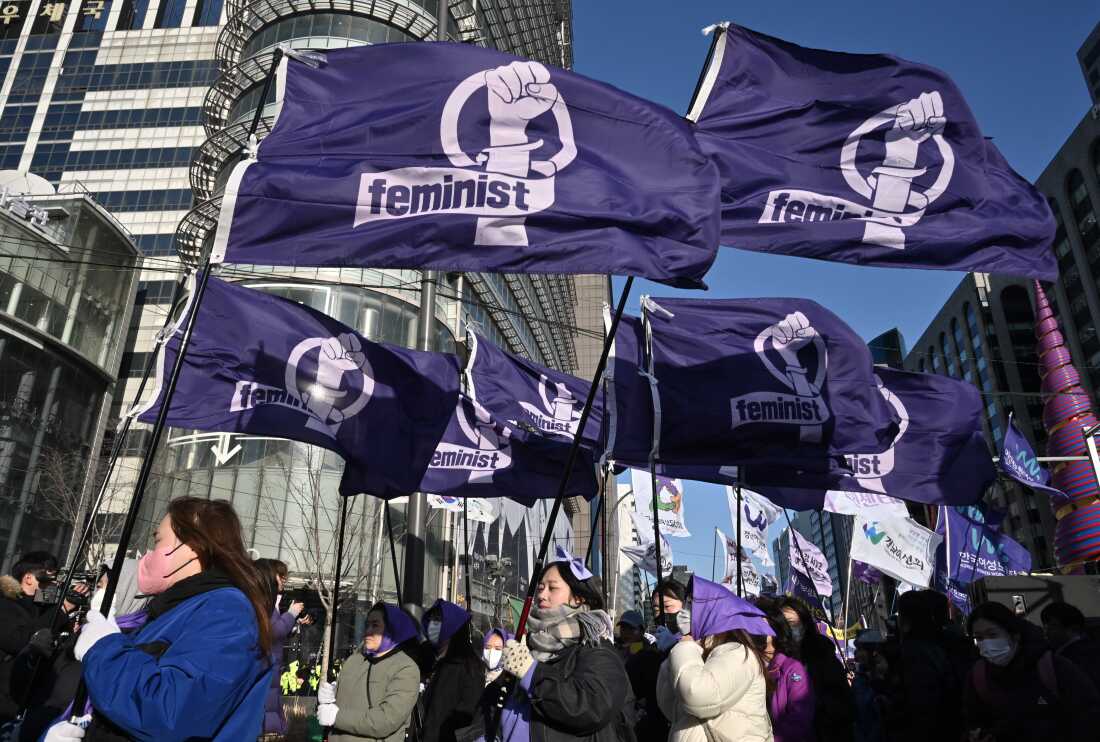 South Korean women carry flags reading 