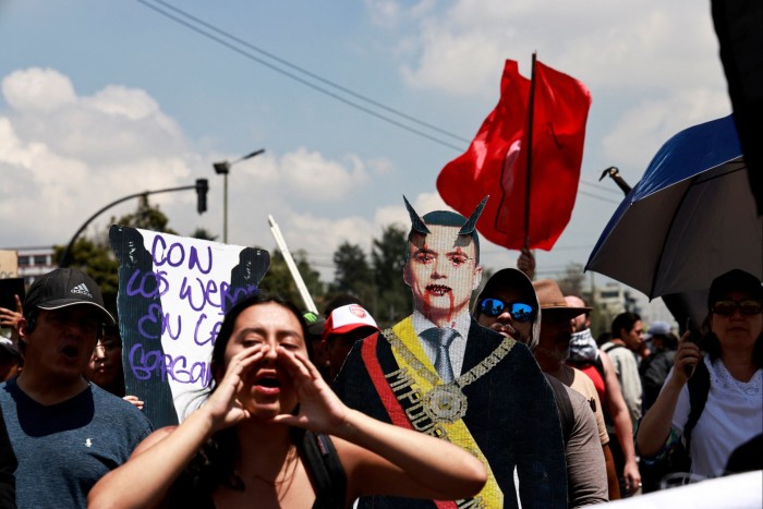 A group of protesters gathered outdoors, with a variety of signs and symbolic displays