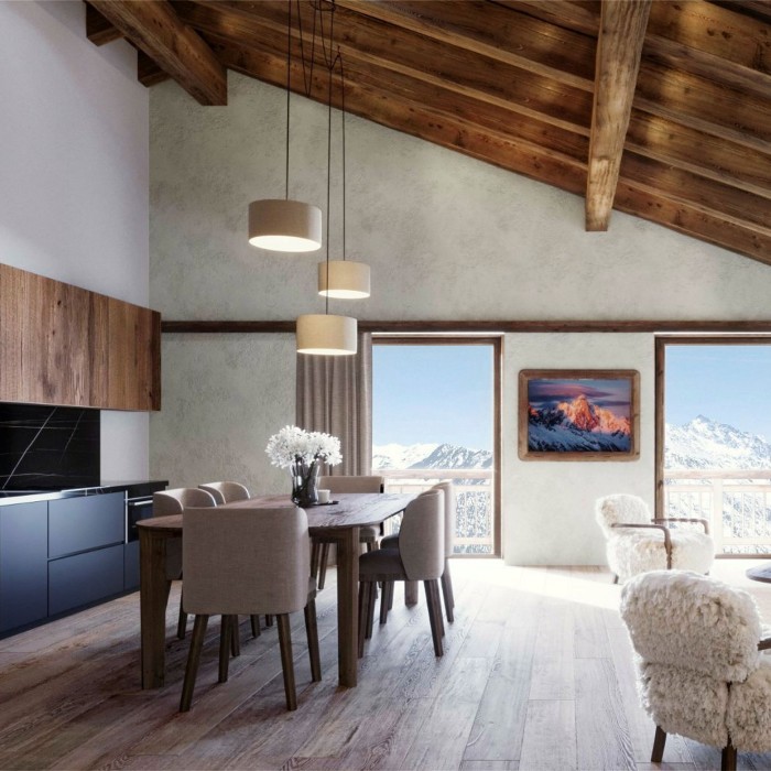 An interior shot of a hotel room, with a dining table, a wooden-beamed ceiling, and picture windows with snowy mountain views