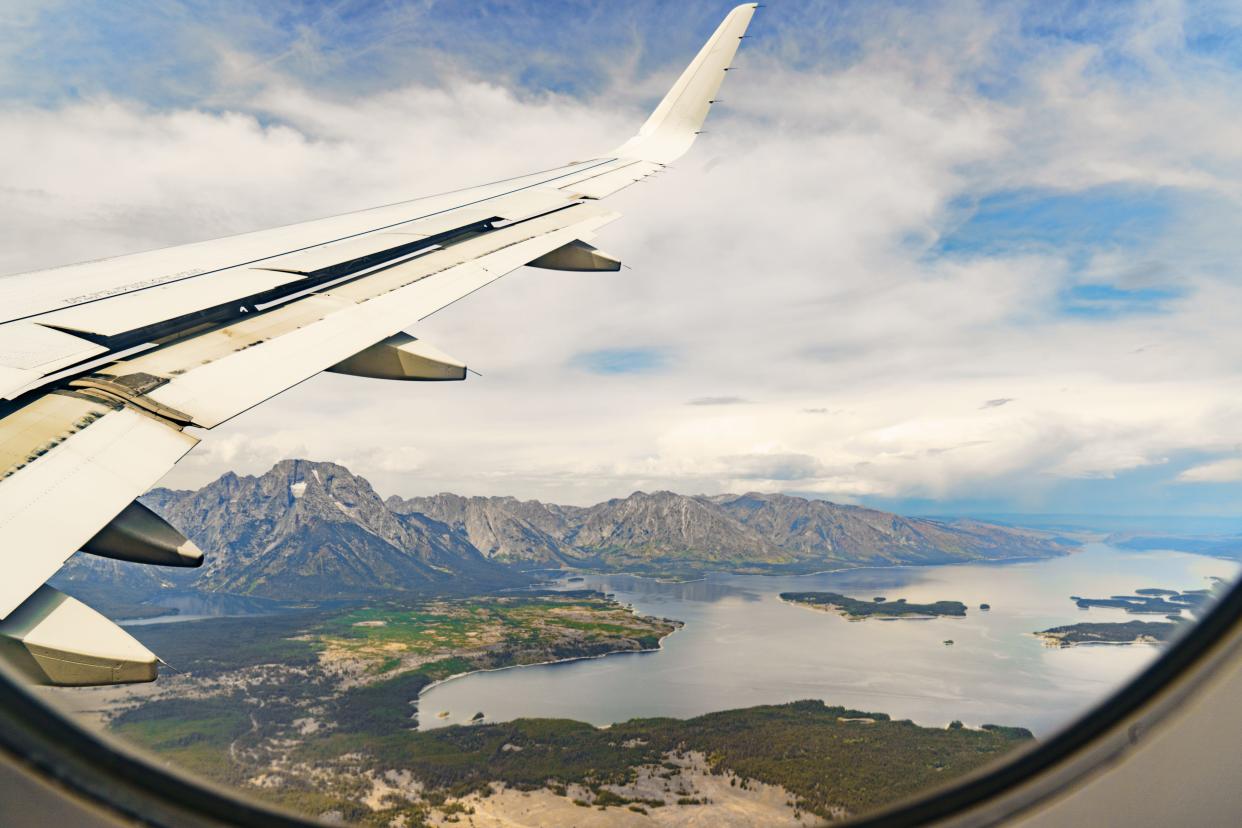 A view out a plane window with the wing on the left and mountains and lakes on the right