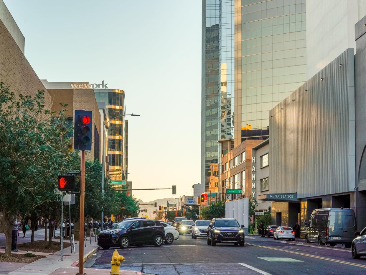 A street in Downtown Phoenix lined with crosswalks and tall buildings with mountains in the distance