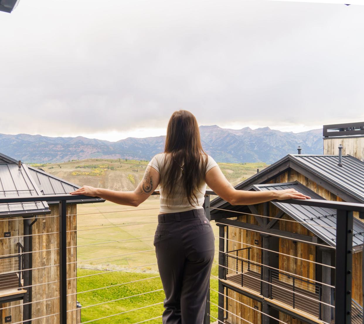 The author on a balcony facing the mountains with two hotel units in front of her.