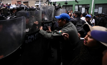 Seguidores del expresidente Evo Morales empujan los escudos de los policías fuera de una comisaría en La Paz (AP Foto/Juan Karita)