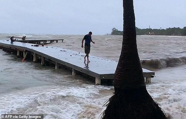 A man walks on a wharf ahead of the arrival of tropical storm Sara in West Bay, Roatan, Honduras on November 14, 2024