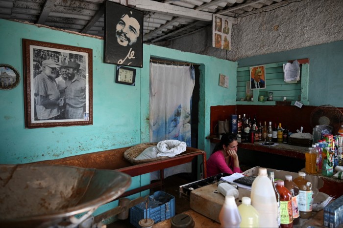 A woman waits for costumers in a cafe displaying pictures of Cuban revolutionaries Fidel Castro and Che Guevara