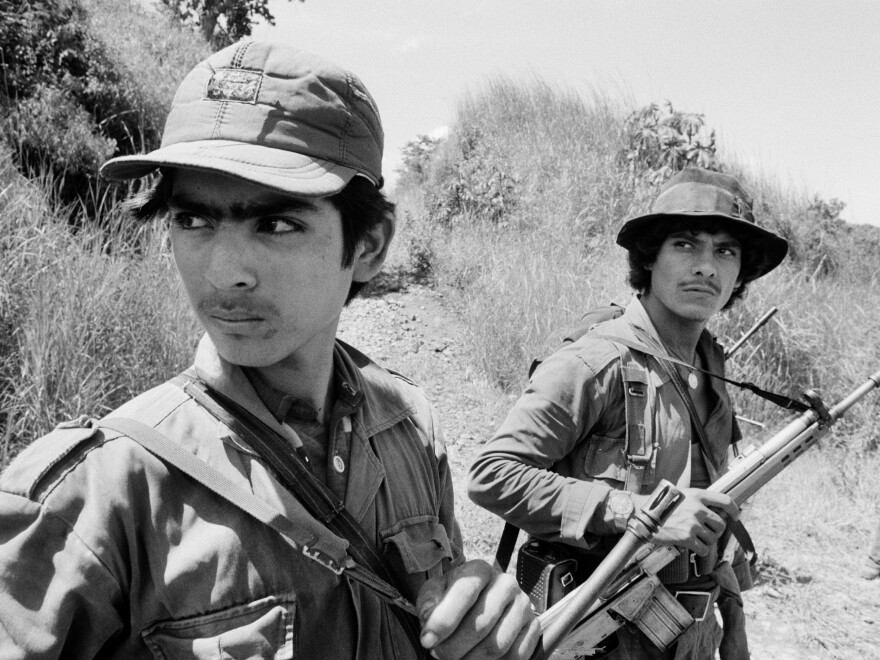 Two guerrillas from the Farabundo Martí Popular Liberation Forces (FPL) watch a low-flying Salvadoran military observation plane near the Guazapa volcano on the road to Suchitoto, El Salvador, on Oct. 21, 1983.