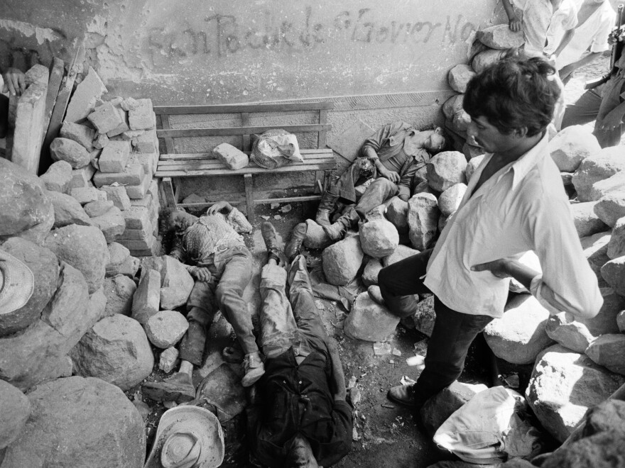 Civilians look over the dead bodies of three civil defensemen killed during an overnight attack by guerrillas from the Farabundo Martí National Liberation Front (FMLN) in Santa Clara, El Salvador, in July 1982.